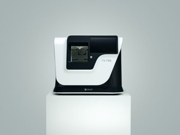 Modern Essilor ES 700 and ES 700M Lens Edging Systems spectrometer on a pedestal against a gray background.